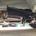 Redfoot Levelling - The underside of a Fiat car with an exhaust pipe and Redfoot Levelling Fiat ‘AutoLift’ System.